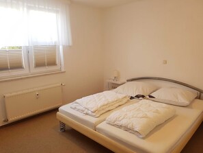 A bedroom with a bed, a nightstand, a lamp, and a radiator.