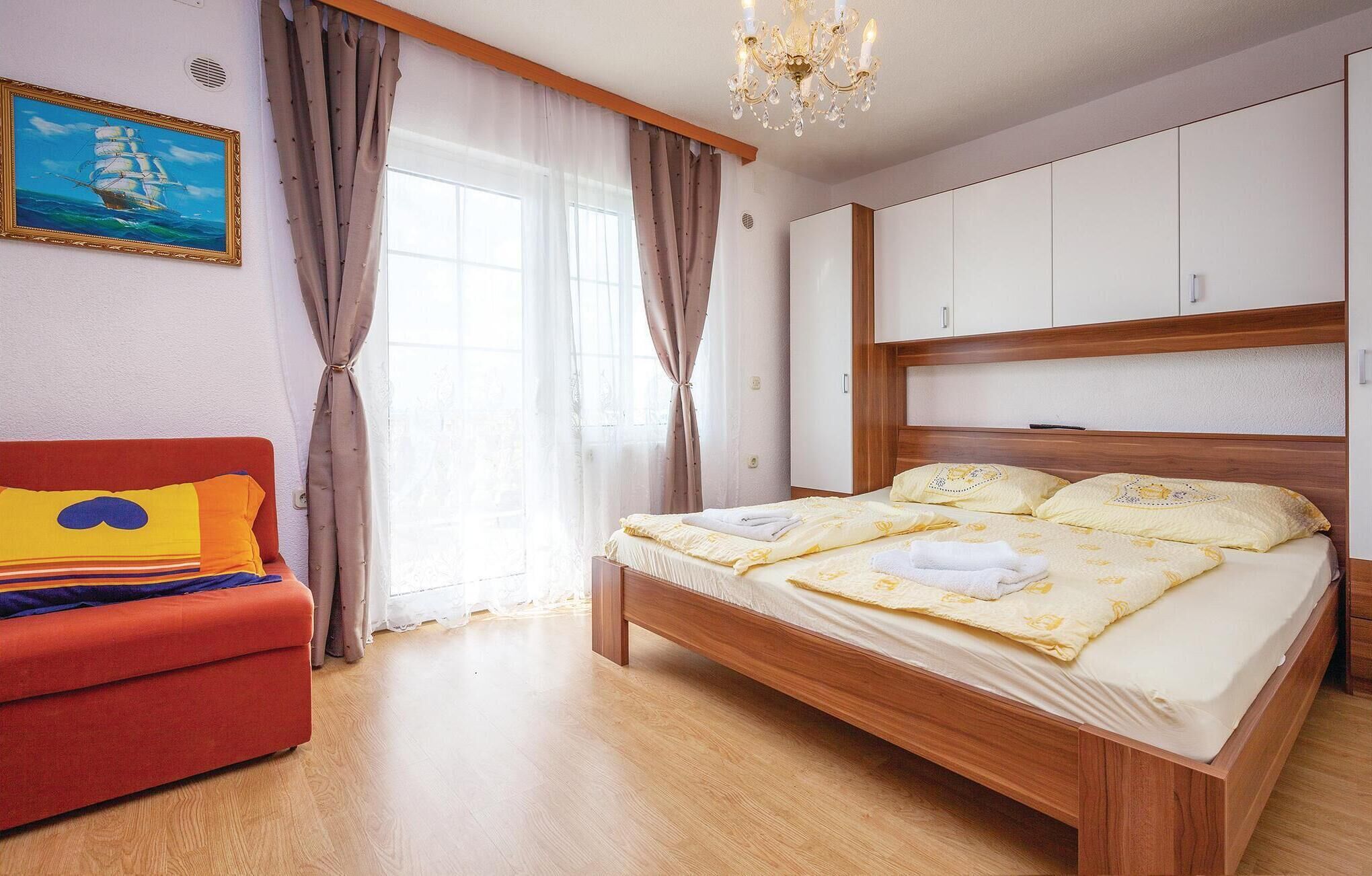 Ein Schlafzimmer mit einem hölzernen Bett, einem roten Sofa und einem großen Fenster mit Vorhängen.