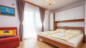 Une chambre à coucher avec un lit en bois, un canapé rouge et une grande fenêtre avec des rideaux.
