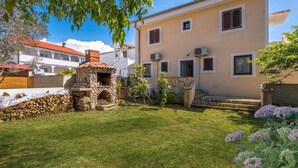 Una casa con un horno de piedra en el exterior, un césped bien cuidado y un jardín lleno de flores.