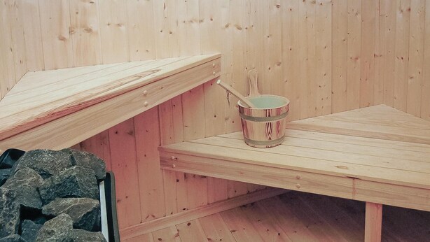 Un sauna en bois avec un banc et un seau.