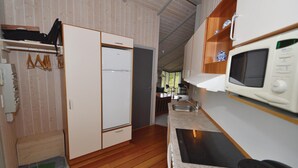 Une cuisine compacte équipée d’un four à micro-ondes, d’une cuisinière et de meubles de rangement en bois.