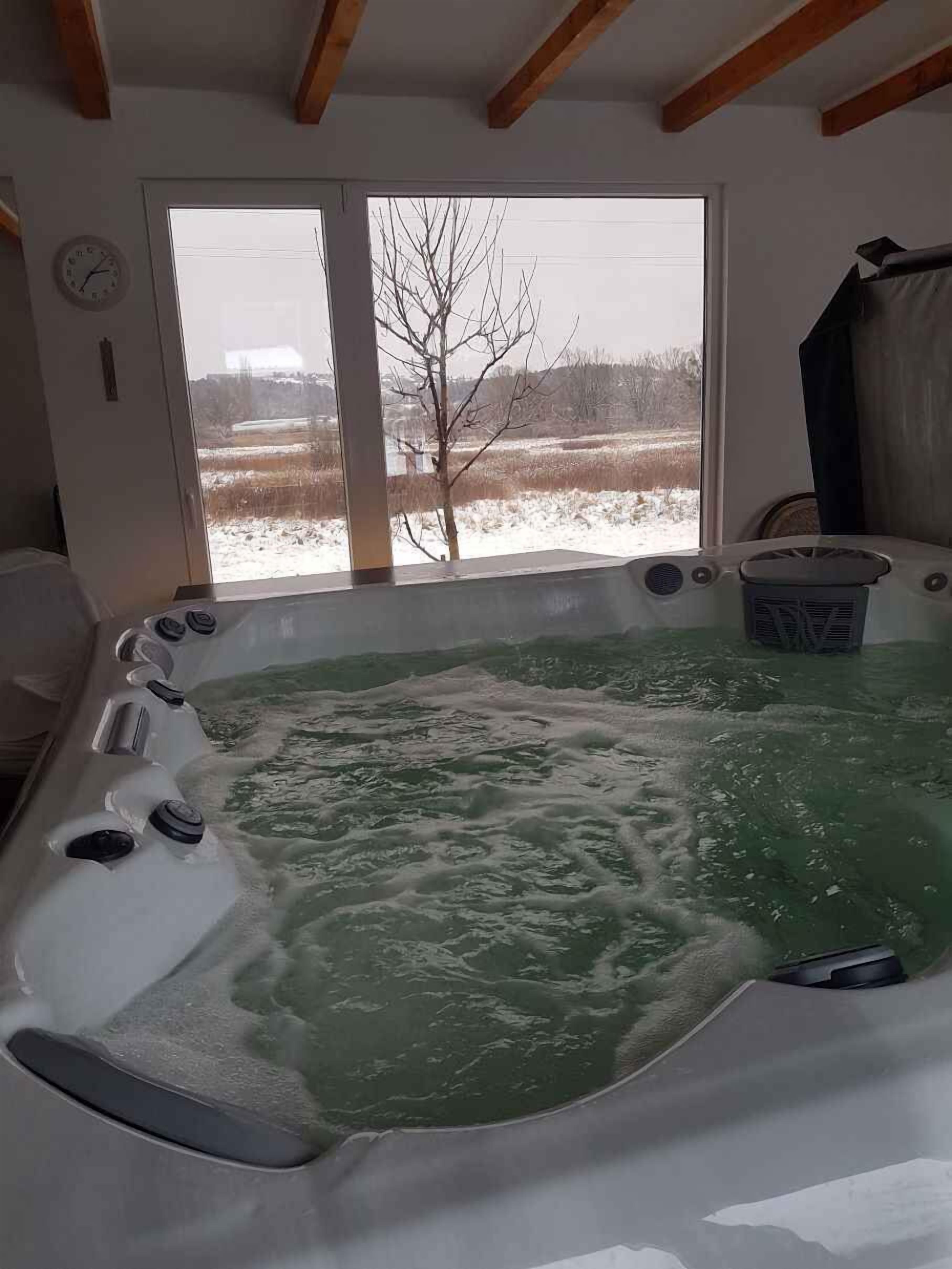 Un bain à remous avec vue sur un paysage enneigé, visible à travers une grande fenêtre.