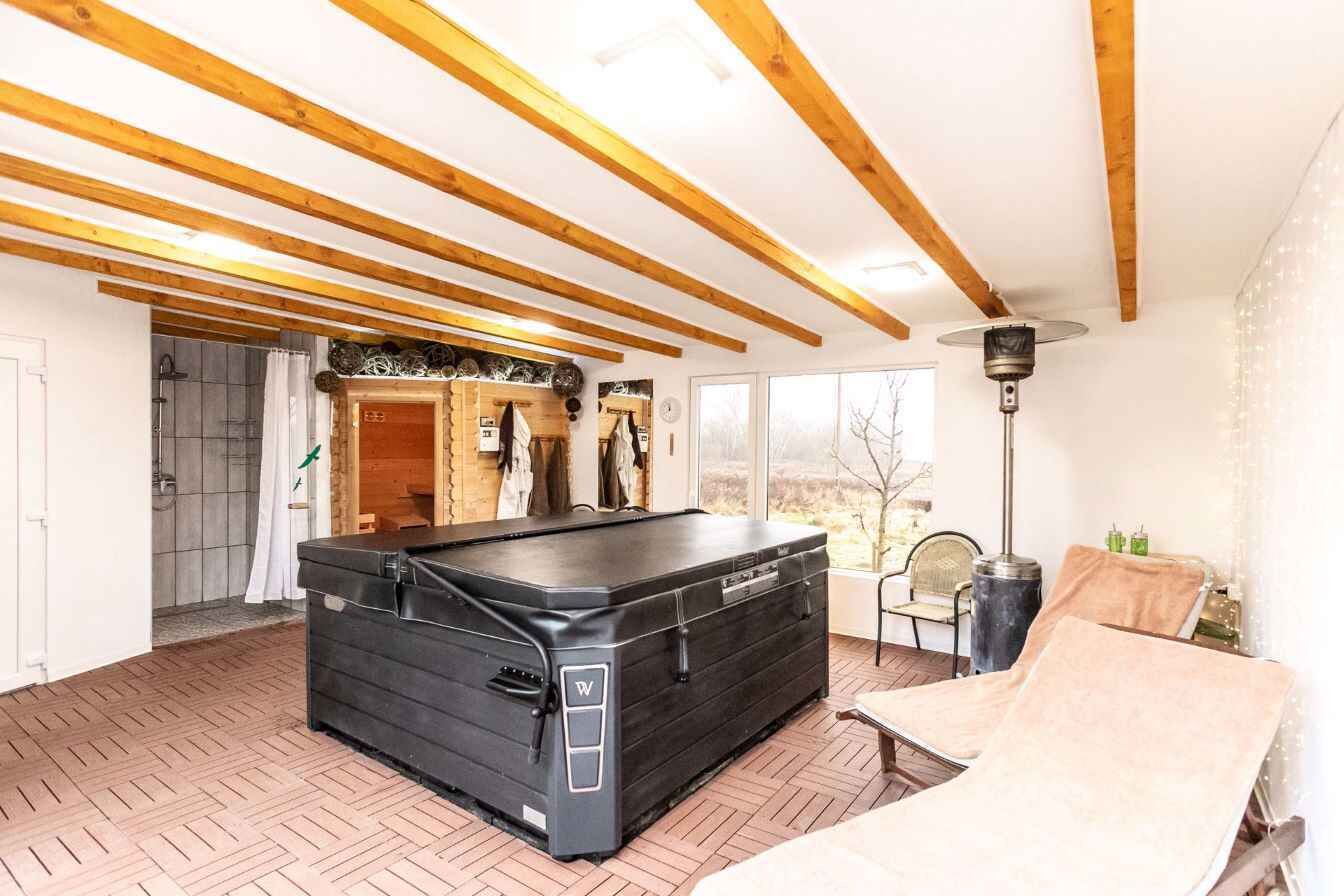 Une salle de spa équipée d’une table de massage, de poutres en bois, d’une grande fenêtre et d’un sauna.