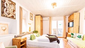 Ein gemütliches Schlafzimmer mit einem großen Bett, Holzmöbeln, einem Fernseher und Balkonblick.