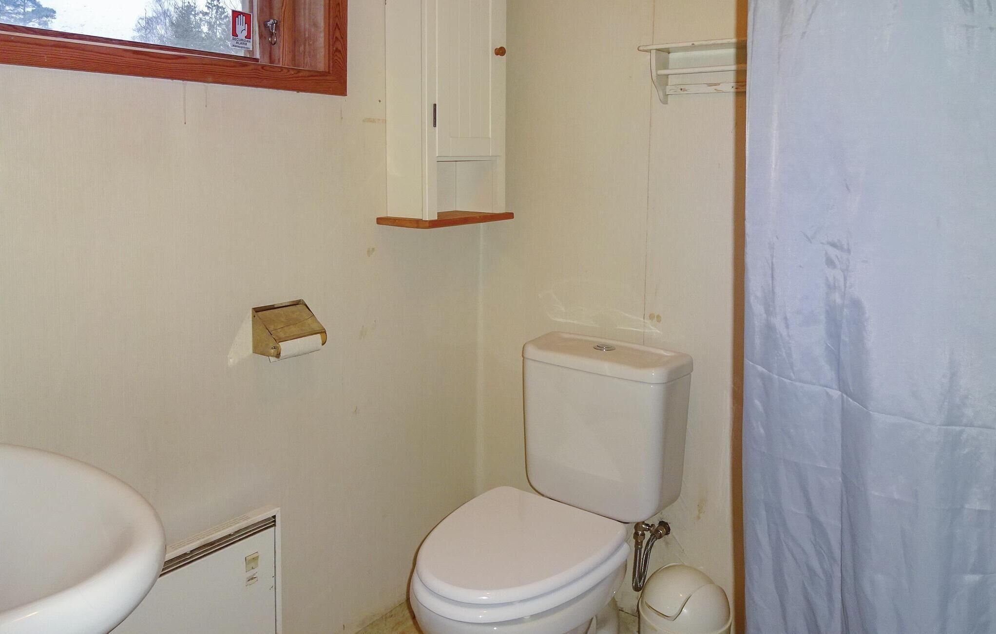 A small bathroom with a toilet, a sink, and a cabinet.