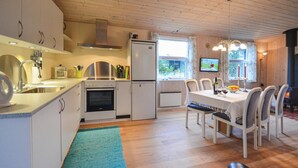Una cocina compacta con electrodomésticos modernos, un comedor con mesa y sillas, y un interior acogedor de madera.