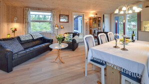 Una habitación acogedora con un sofá de cuero, una mesa de comedor con velas, y vistas al exterior a través de amplias ventanas.