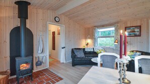 Una habitación acogedora con una estufa de leña, un sofá, una mesa de comedor y una ventana con vistas.