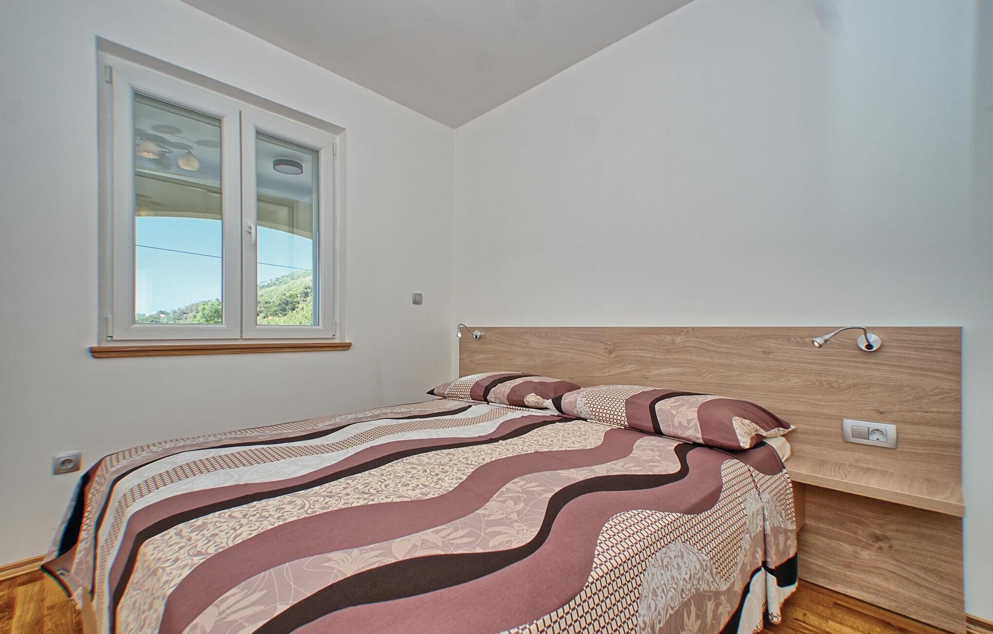 A bedroom with a bed, a window, and a wooden headboard.