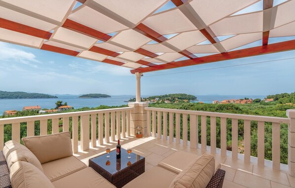 Un espacio de estar al aire libre con techo y vistas al mar y a las colinas.