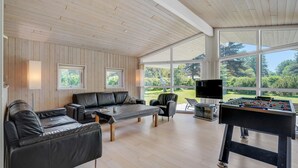 A spacious room with a wooden ceiling, a sofa, a coffee table, a TV, and a foosball table. - Nice home in Væggerløse with sauna (Væggerløse)