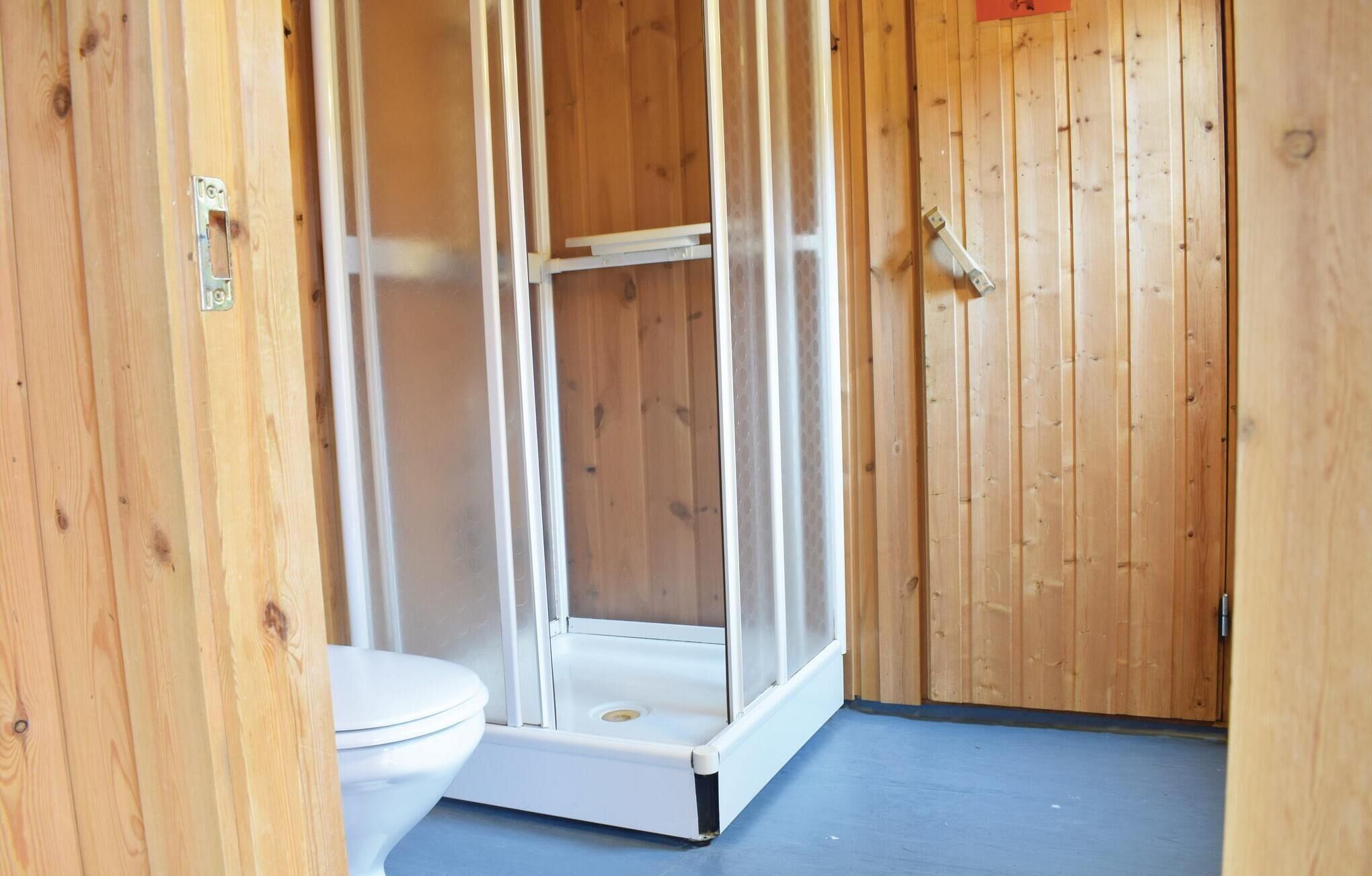 A small, enclosed bathroom with a toilet and a shower stall.