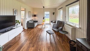 A modern living room with a flat-screen TV, grey sofas, a coffee table, and a fireplace. - Cozy home in Sydals with sauna (Sydals)