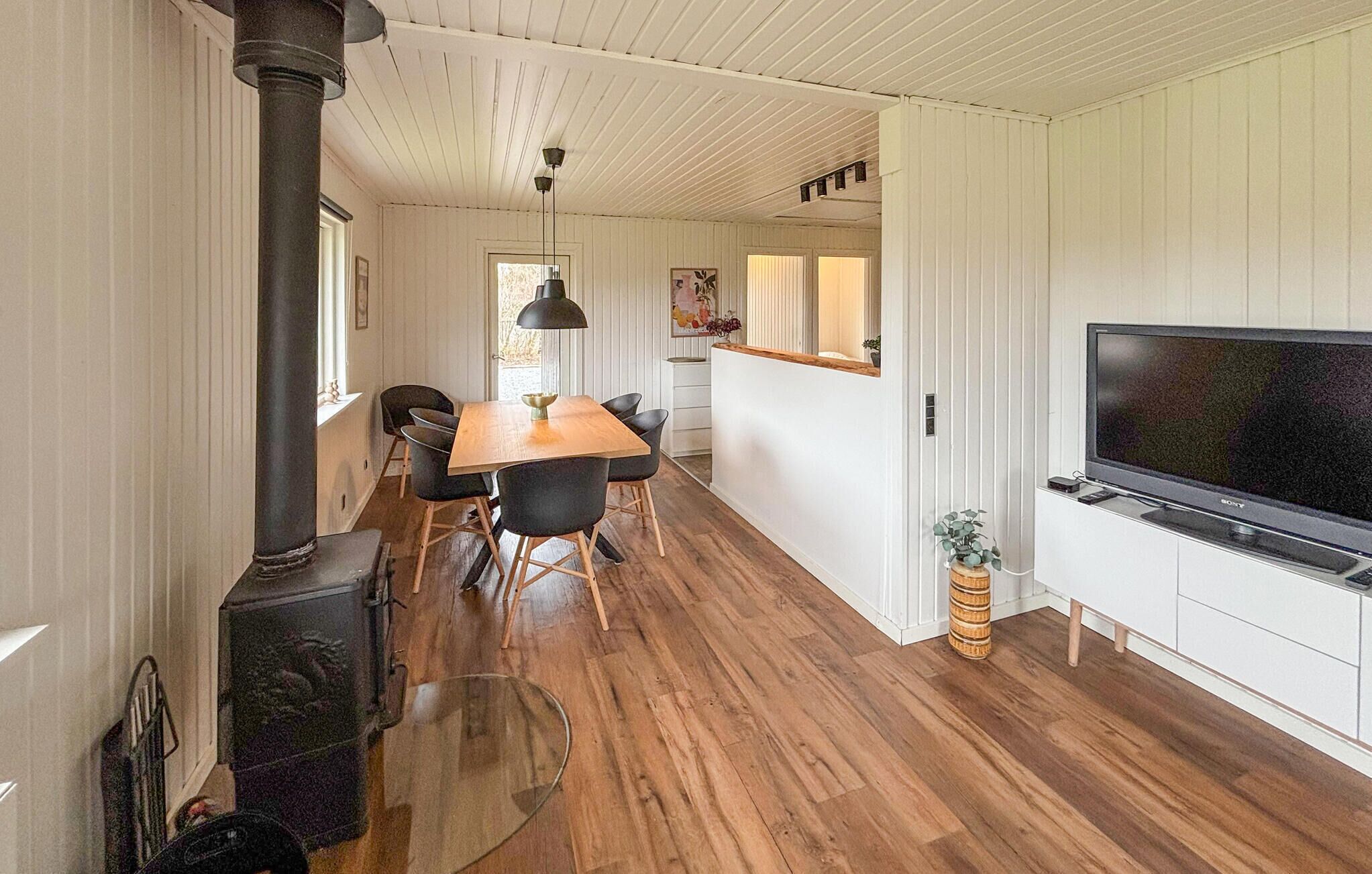 Una cocina moderna con una televisión de pantalla plana grande, suelo de madera y una isla central.