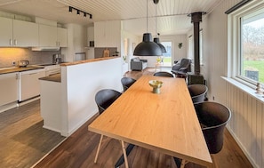 A modern kitchen with white cabinets, a wooden island, and a dining area with a long table and chairs.