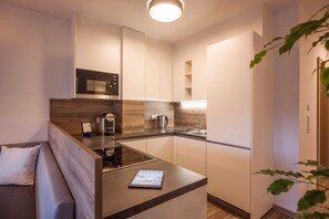 A modern kitchen with a built-in microwave, a coffee maker, and a tablet on the counter. - Apartment Zillertal Deluxe - Aparthotel **** AlpTirol (Kaltenbach)