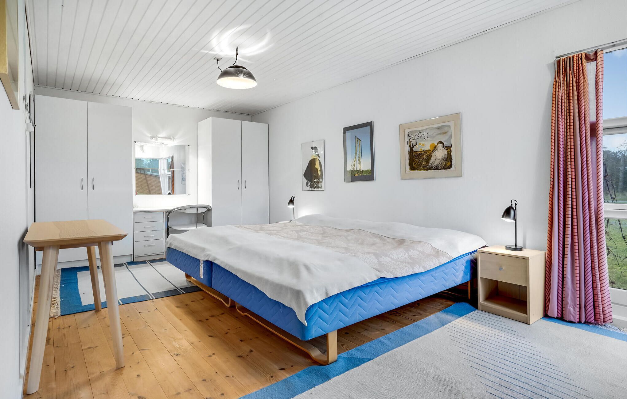 A bedroom with a bed, a desk, and a wardrobe.
