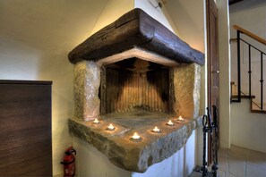 Cozy fireplace with candles and a traditional staircase in the background.