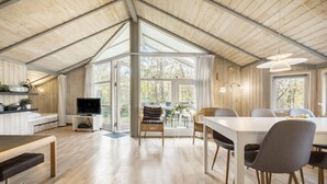 Ein geräumiges Loft mit hohen Decken, Holzwänden und großen Fenstern mit Blick ins Freie.