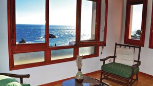 A room with a view of the ocean through large windows, a chair, and a small table with a vase. - Nice home in Tossa de Mar with WiFi (Tossa de Mar)