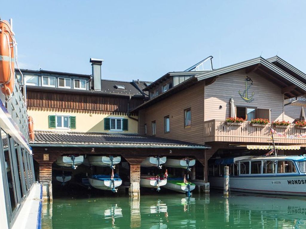 A boat docked at a marina with a building featuring a balcony with flower boxes.