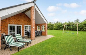 A brick house with a patio area featuring two striped lounge chairs and a table. - Awesome home in Tarm with sauna (Tarm)