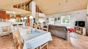 A spacious living area with a high ceiling, wooden beams, a dining table with chairs, a sofa, and a television. - Awesome home in Tarm with sauna (Tarm)