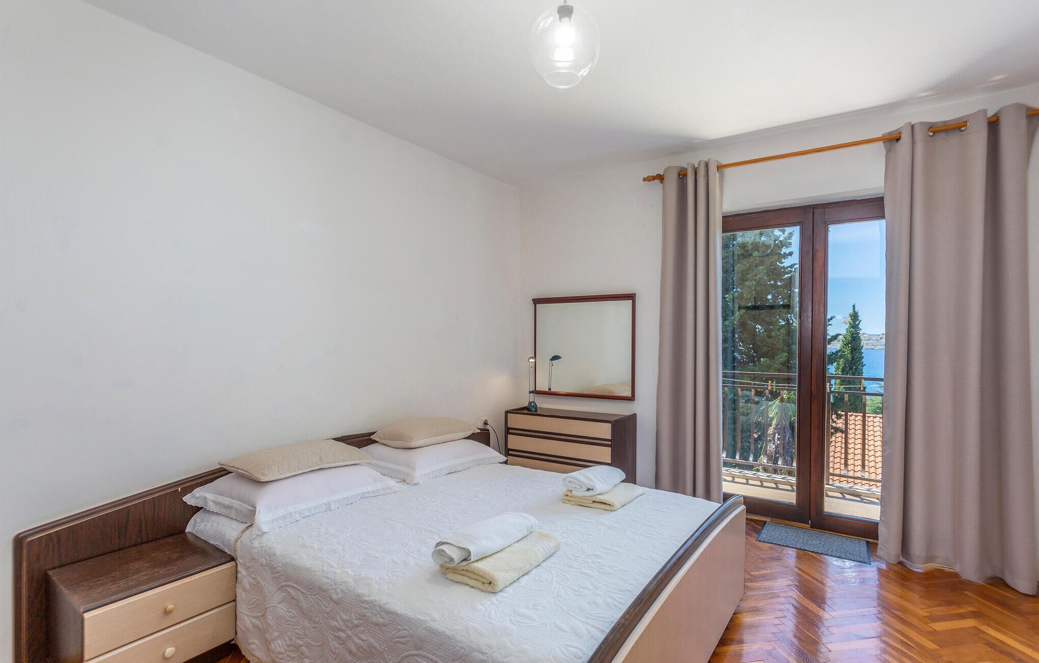 Een slaapkamer met een bed, nachtkastjes, een spiegel en uitzicht op de omgeving.
