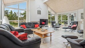 Ein geräumiges Wohnzimmer mit großem Fernseher, Ledersofas und einem Holztisch.