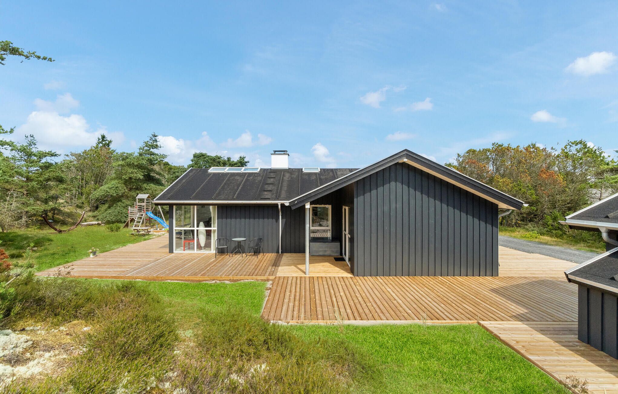 Une maison moderne de plain-pied dotée d’une grande terrasse et d’un espace extérieur couvert.