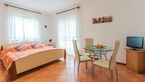 Un dormitorio con cama, una mesita con sillas, televisor y un cuadro en la pared.