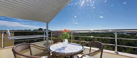 A balcony with wicker furniture, a table with a lace tablecloth, and a vase with flowers.