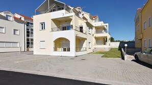 A multi-story residential building with balconies, a parking area, and a car parked in front. - Cozy apartment in Vodice with house sea view (Vodice)
