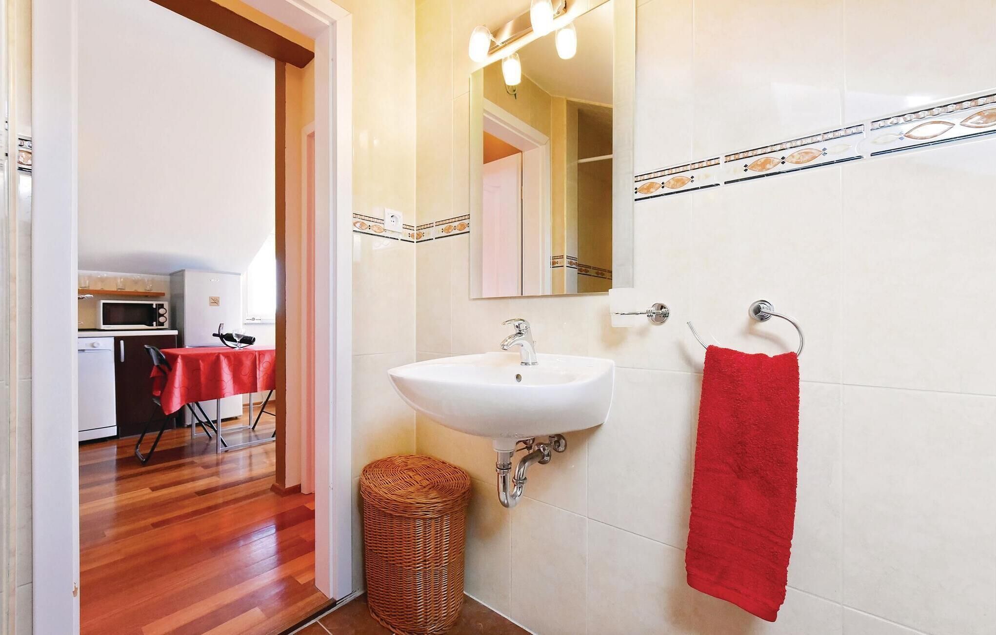A bathroom with a white sink, a red towel, and a mirror above the sink.