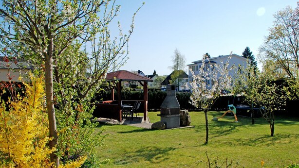 Un jardin avec un belvédère, un barbecue et un four en pierre.