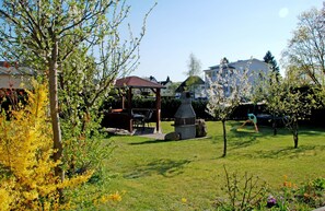 A backyard with a gazebo, barbecue grill, and a stone oven.