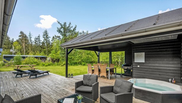A covered outdoor patio with wicker furniture, a hot tub, and a wooden deck. - Beautiful home in Skjern with sauna (Skjern)