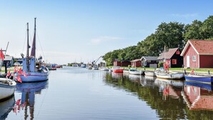 A calm harbor with several boats docked, a red building with a sloped roof, and a clear blue sky. - Beautiful home in Skjern with sauna (Skjern)