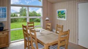 Un comedor con una mesa y sillas de madera, una lámpara y vista a zonas verdes.