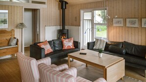 Una sala de estar acogedora con chimenea, sofás a rayas y piso de madera.