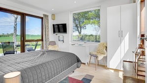 Un dormitorio con cama, televisor, ventana con vistas a follaje y una escalera.