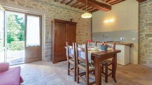 Cocina rústica con paredes de piedra, mobiliario de madera y una mesa de comedor preparada para cuatro comensales.