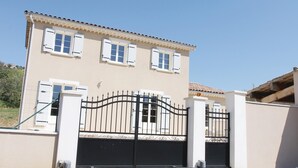 Ein zweistöckiges Gebäude mit einer beige farbenen Fassade, weißen Fensterläden und einem schwarzen Metallgitter.