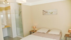 Ein Hotelzimmer mit einem Bett, zwei Nachttischlampen, einem Nachttisch, einer Glasdusche und einem Wandbild.