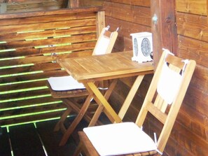 A wooden table with two chairs, a small white speaker, and a wooden bench. - Bio living Waldblick room with kitchen - Bio Bauernhof Mondsee Familie Schafleitner-Kroiß (3 flowers) (Guggenberg)
