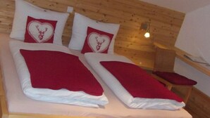 Une chambre de style cabane en bois, avec deux lits, chacun recouvert d’une couverture rouge et agrémenté d’oreillers en forme de cœur.