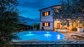 Ein zweistöckiges Haus mit Swimmingpool, Steinmauer und Gartenmöbeln.