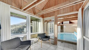 A covered outdoor area with a pool, two chairs, and a table. - Stunning home in Hvide Sande with sauna (Hvide Sande)