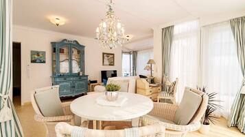 A room with wicker furniture, a chandelier, a cabinet, and a television.
